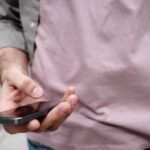 A man holding a cell phone, representing the best nonprofit text platform for communication and outreach.